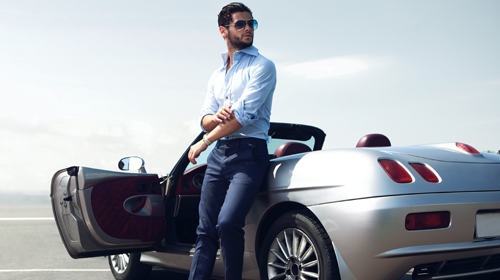 man standing in front of a luxury convertible